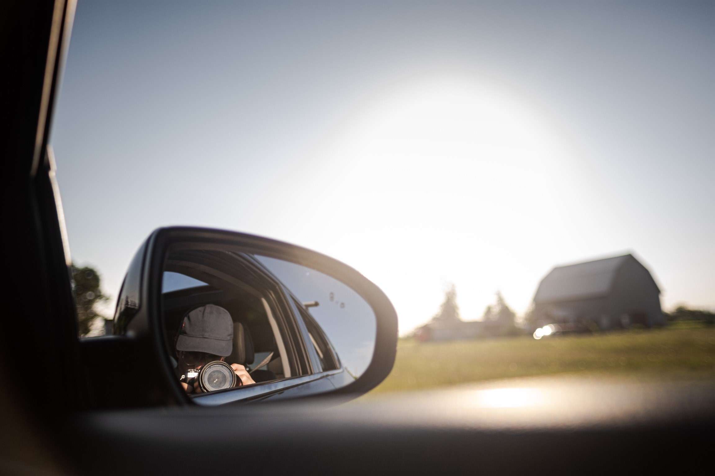 Tyler Colburne takes a picture of his reflection in a car side mirror with the sun in the background.