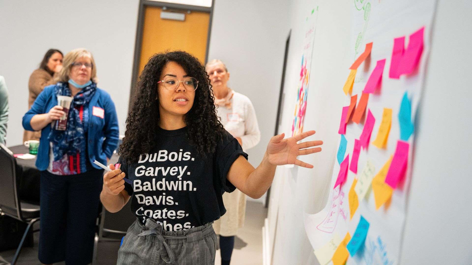 Woman pointing at colourful sticky notes on a wall