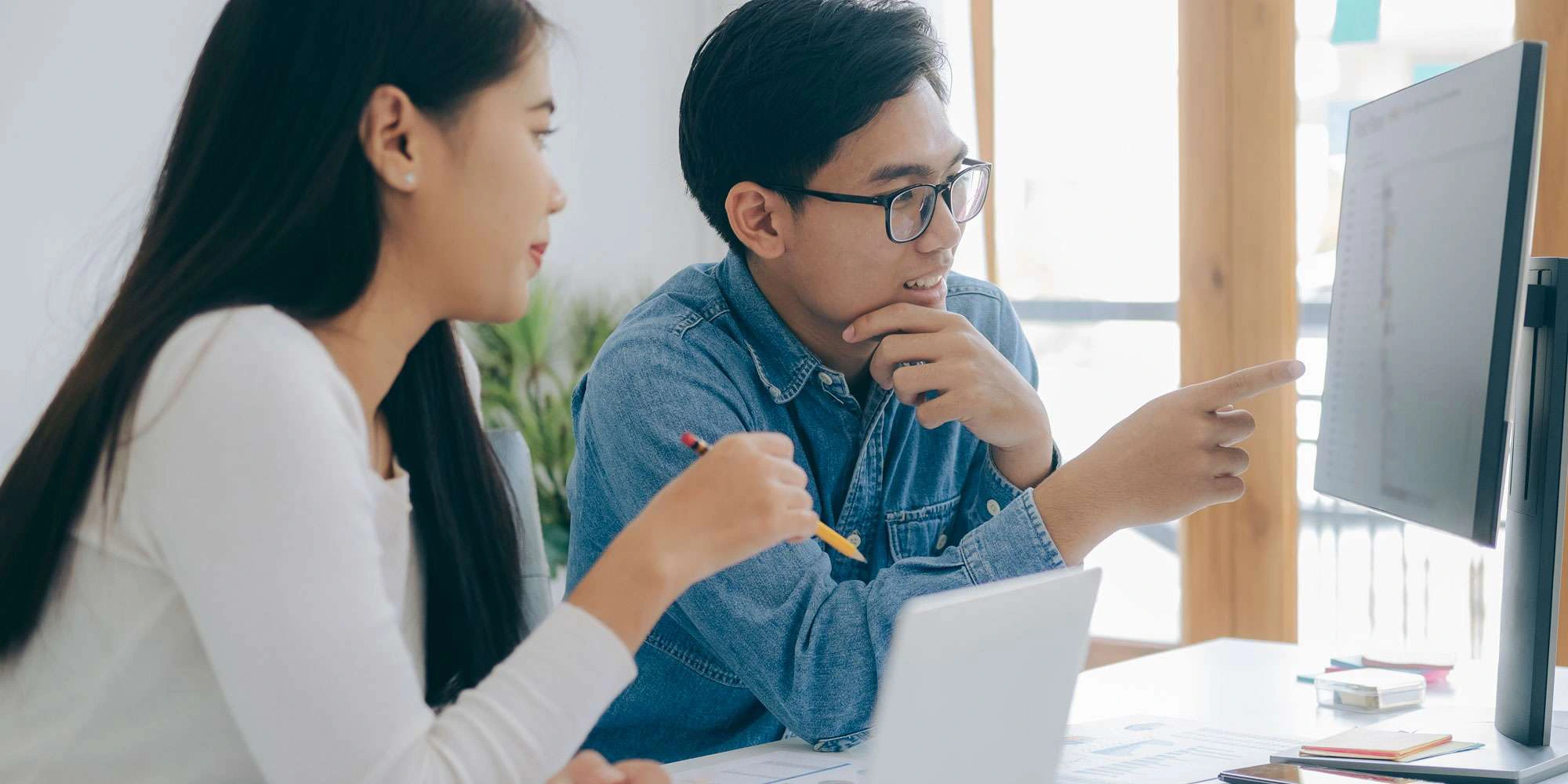 A photo of two people collaborating in front of a computer.
