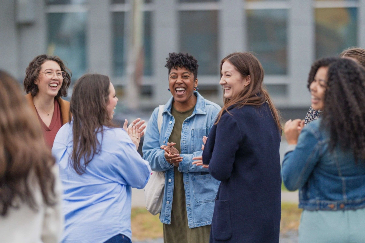A photo of 6 people smiling and laughing and enjoying themselves outside.
