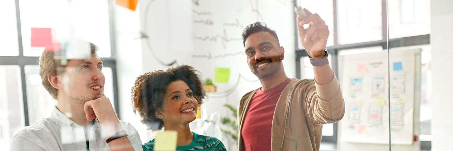 Photo of two people collaborating and writing on a whiteboard.