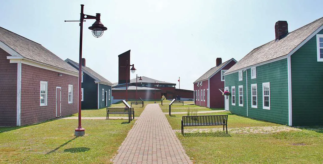 Impact Story. A photo of buildings with green grass surrounding them, a few bunches and a large lamppost. 